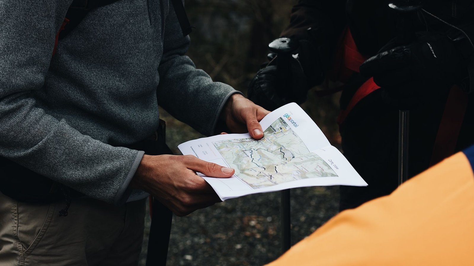 Two outdoor travelers reviewing a paper topographic map before entering the field.