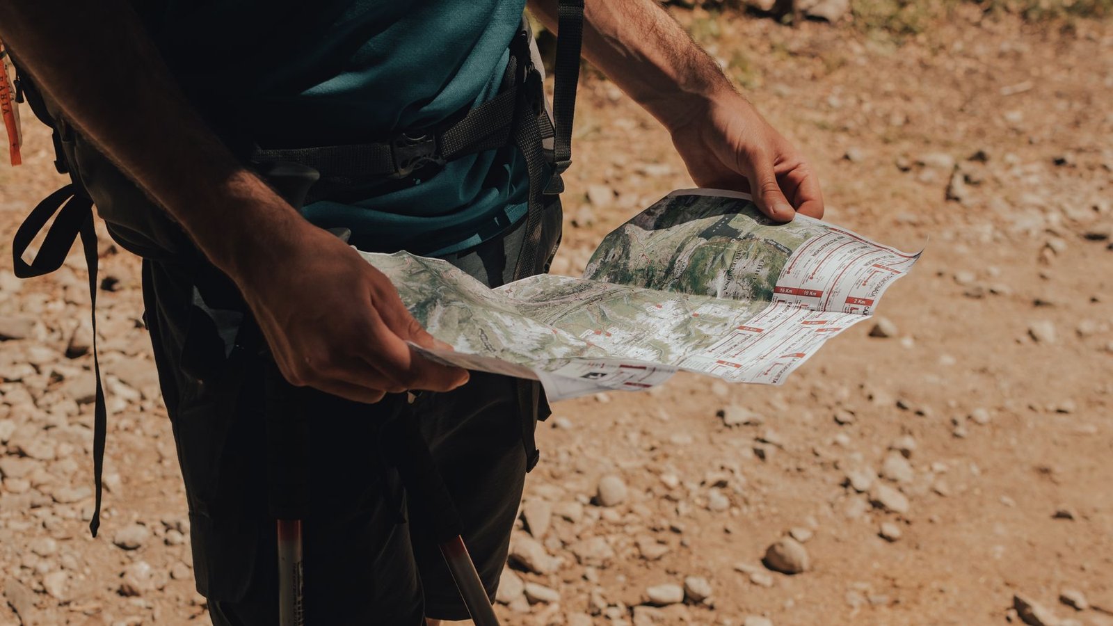 Backcountry traveler studying a detailed trail map on rocky terrain.