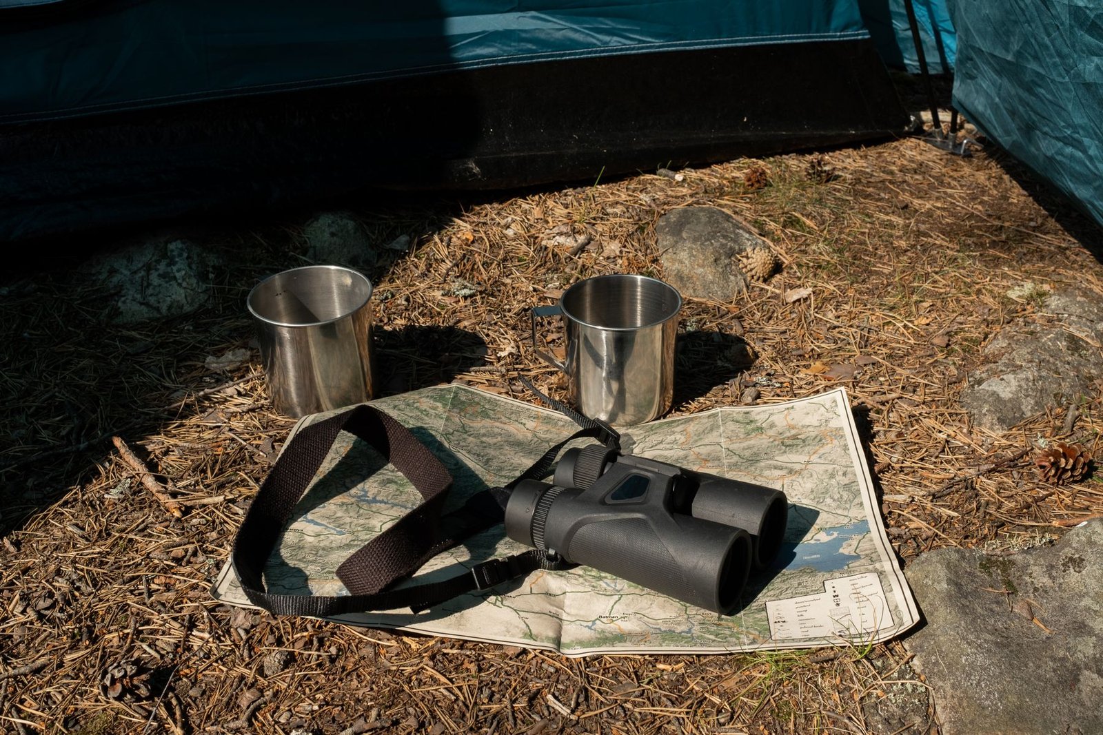 Binoculars resting on a topographic map outside a tent for hunt planning and field scouting